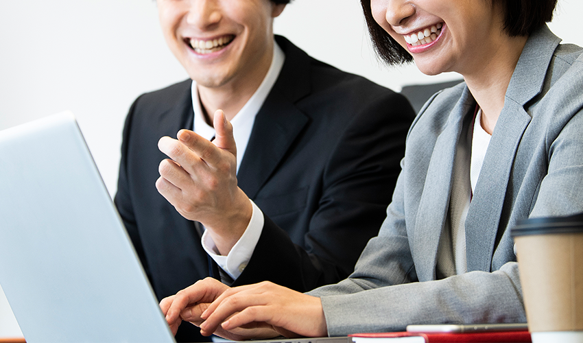 PC画面を見ながら談笑する男女